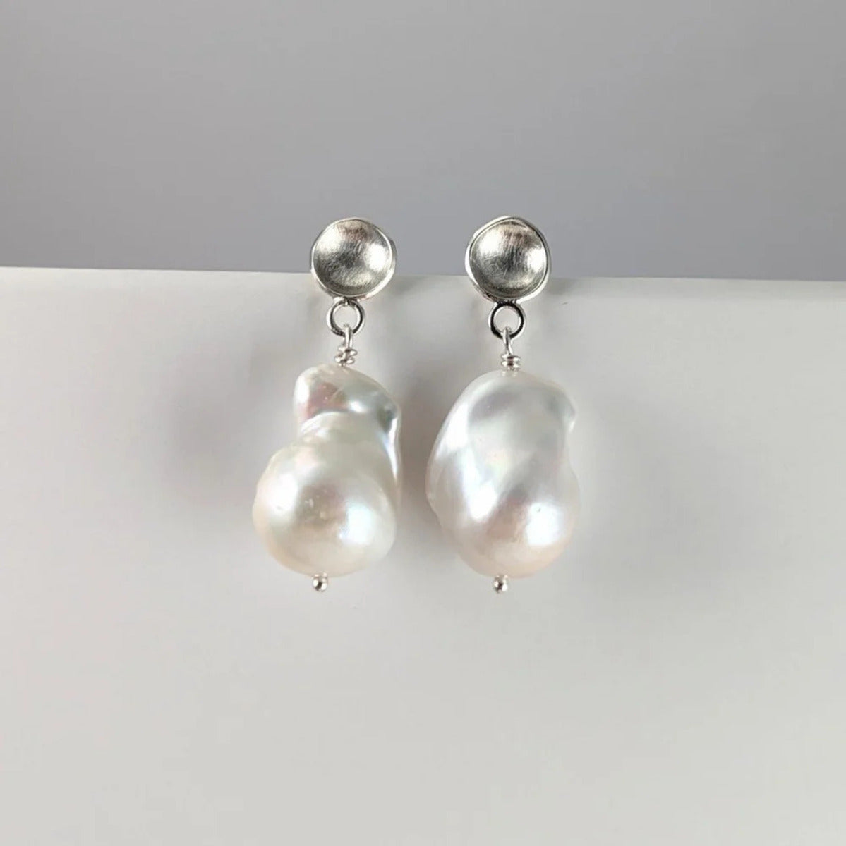 Domed silver stud earrings with large white baroque pearls
